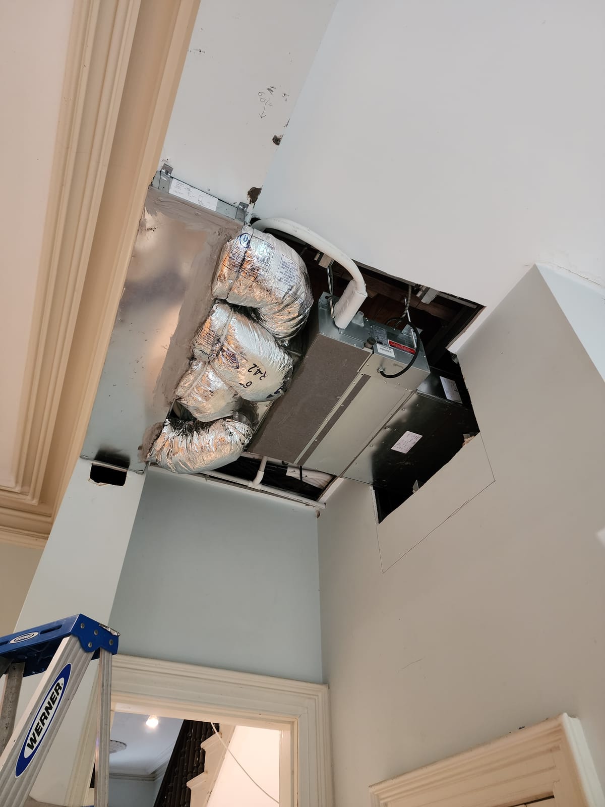 Ducted air handler being installed above ceiling during renovation