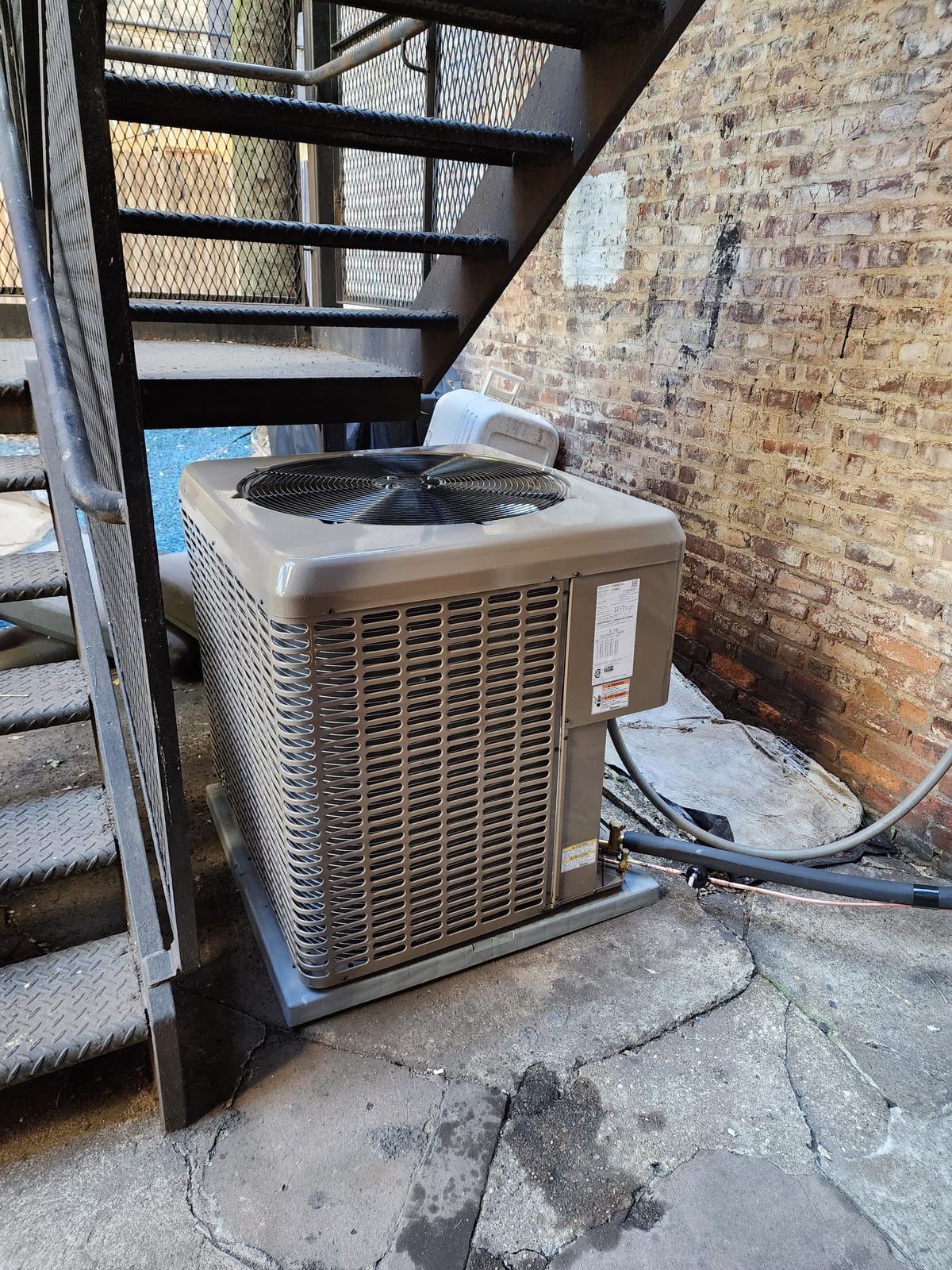 Mini split condenser on fire escape mounting bracket