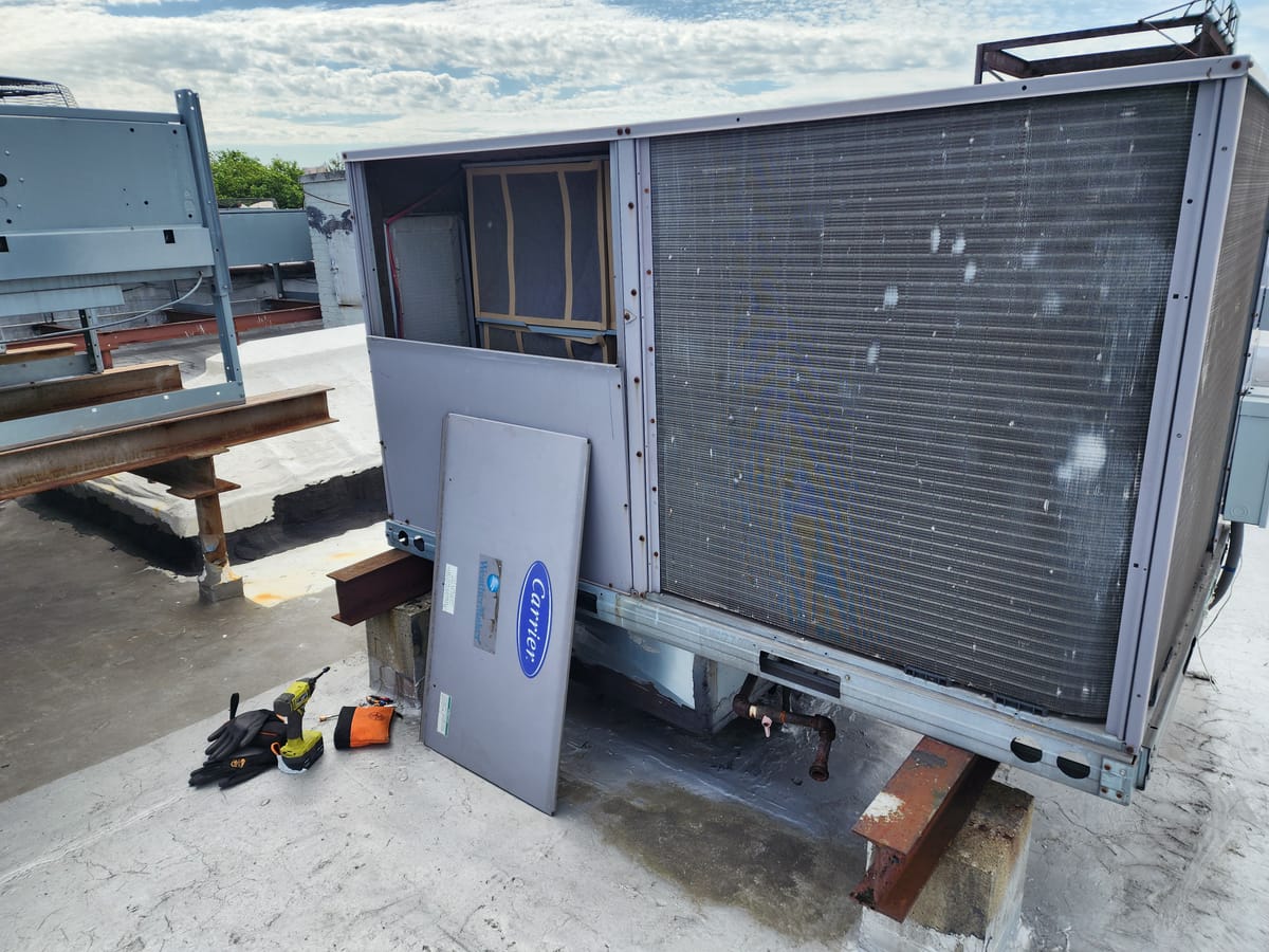 Technician using recovery machine on rooftop condenser